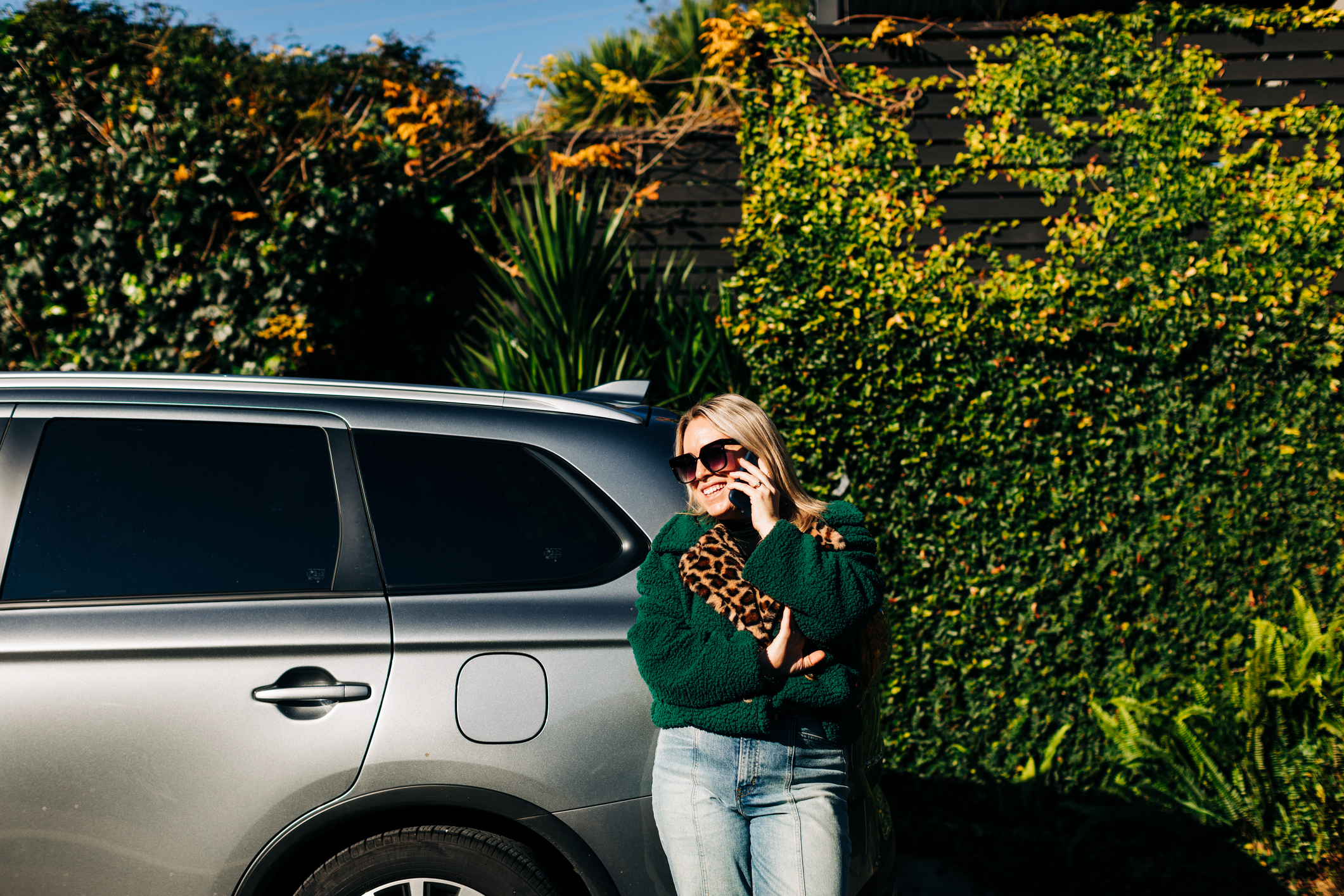 Woman standing beside car holding mobile phone